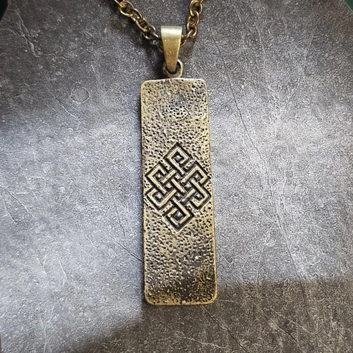 Brass pendant with engraved Endless Knot – spiritual jewelry symbolizing eternal harmony and interconnectedness, handcrafted by Snow Cat Jewelry