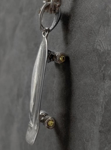 Side view of 925 sterling silver surfskate pendant with yellow cubic zirconia wheels – skateboard necklace by Snow Cat Jewelry