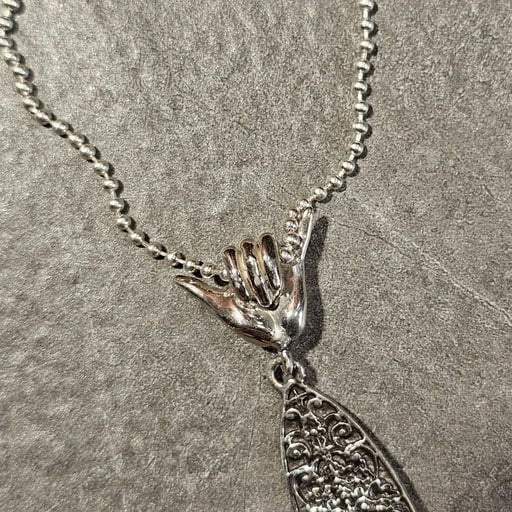 Close-up of Shaka hand bail and top of Balinese carved surfboard pendant in sterling silver – Ocean Spirit necklace by Snow Cat Jewelry