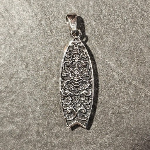 Front view of handcrafted sterling silver surfboard pendant engraved with Barong Balinese motif – spiritual surf jewelry by Snow Cat Jewelry